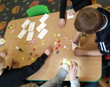 Dzieci z Przedszkola „Pomysłowy Przedszkolak” podczas wykonywania wielkanocnych kartek metodą quillingową